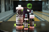 Various sized bottles of TruCut Conditioner in front of a bowling ball on a table in a bowling alley